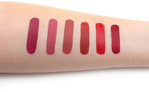 Sechs verschiedene Lippenstiftfarben auf Haut, von dunklem Pink bis Rot.