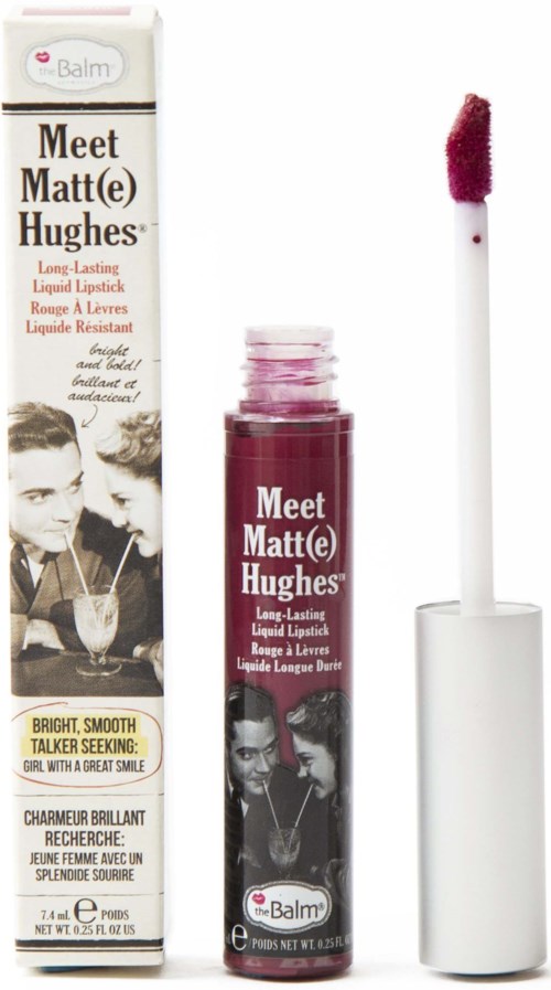Læbegloss med mørk rosa farve og hvid applikator, ved siden af emballage med retro billeder af kvinder.