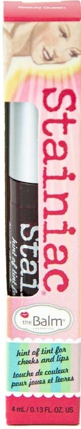 Læbepommetube med pink og hvidt design, med et billede af en kvinde øverst, mærket "Stainiac" af theBalm.