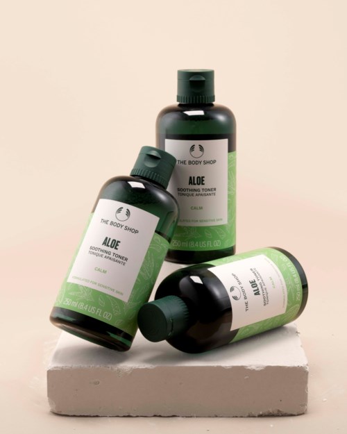 Tre flasker med Aloe beroligende toner og en flaske Aloe beroligende ansiktsvask på en hvit plattform.