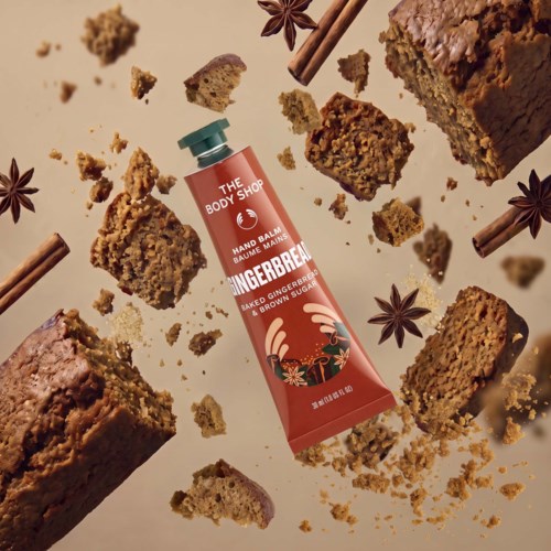 Ein Handbalsam mit Gingembre-Duft umgeben von zerbrochenen Lebkuchenstücken und Gewürzen.