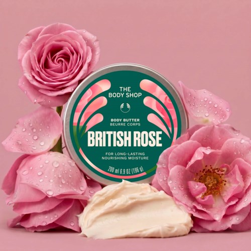 En krukke med British Rose kroppsbutter omgitt av rosa roser med vanndråper på bladene.
