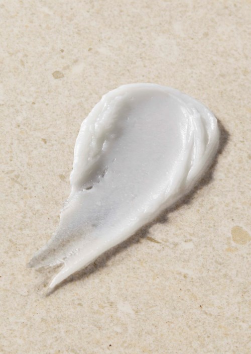 Eine Portion weiße Creme oder Lotion auf einer beigen Oberfläche.