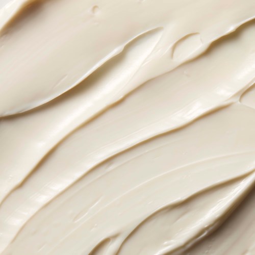 nærbilde av kremet, glatt, lys beige hudpleieprodukt med synlig tekstur og myke riller.