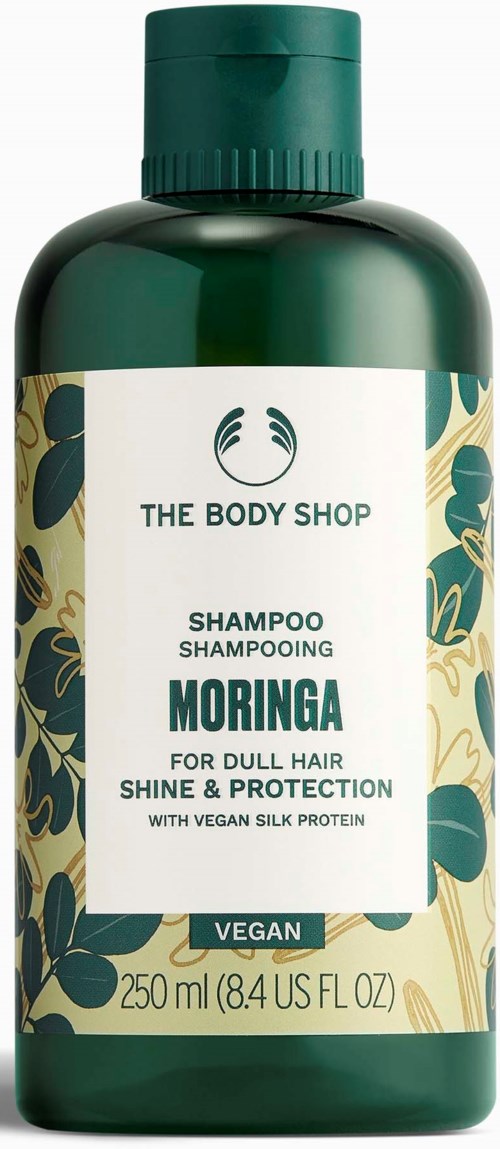 A green bottle of The Body Shop shampoo labeled 'Moringa' for dull hair, shine, protection, vegan, 250 ml.