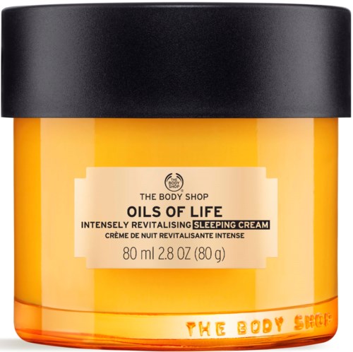 Ett glas av The Body Shop Oils of Life sovkräm med svart lock, gul behållare och produktmärke.