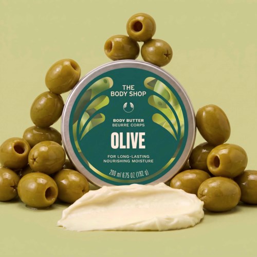 Oliven kroppssmør beholder omgitt av grønne oliven og litt krem nederst.