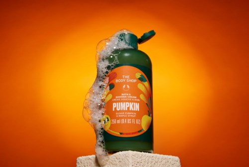 Pumpa duftende dusjgeléflaske fra The Body Shop med skum og oransje bakgrunn.
