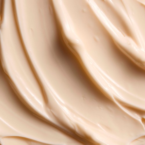 Kremete beige hudpleieprodukt med myk, jevn tekstur i sikk-sakk mønster.