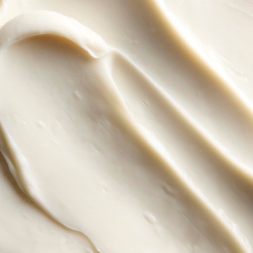 Krem eller lotion som er jevnt fordelt i myke, kurvede linjer med en myk, kremaktig tekstur.