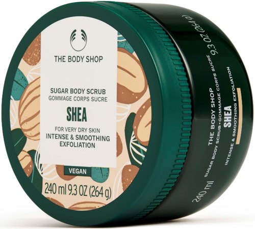 En grön behållare av The Body Shop Shea Sugar Body Scrub med tropiska blad- och nötillustrationer.
