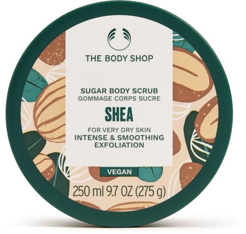 En rund behållare av The Body Shop Shea Sugar Body Scrub med illustrationer av sheanötter och nötter runt etiketten.