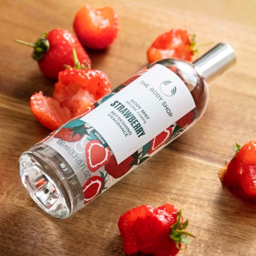 Kuva, jossa on 'Strawberry'-vartaloväline ja tuoreita mansikoita puupöydällä.