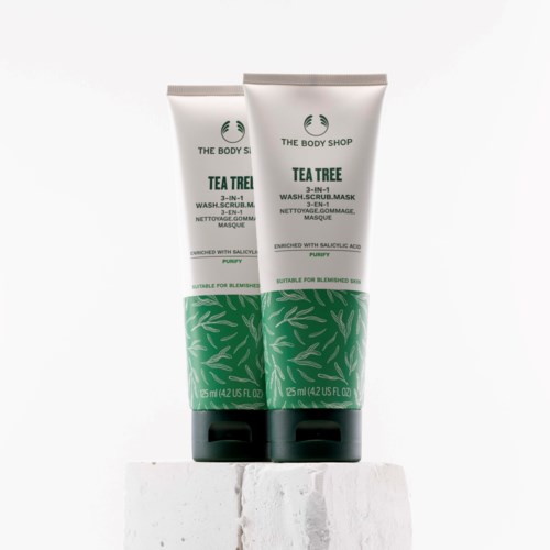 To rør av The Body Shop Tea Tree 3-i-1 vask, skrubb og maske med grønt bladdesign og svarte hengsler.