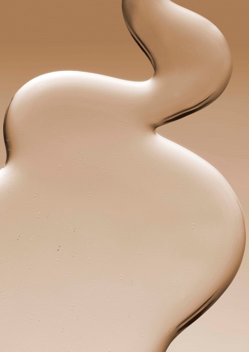 En spiral av lys beige krem eller lotion med jevn tekstur, som flyter i en rolig kurve.