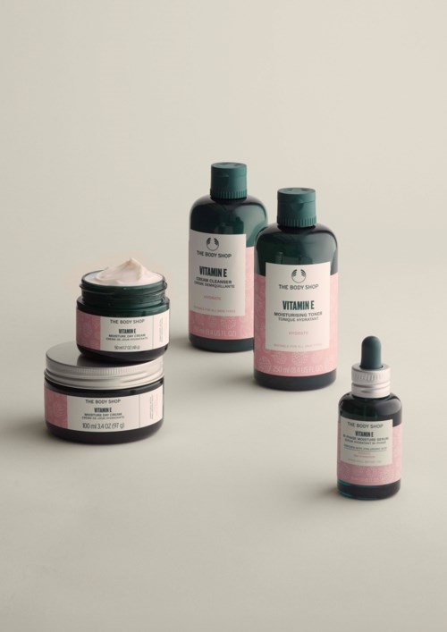 Skincare products with labels for vitamins E and C in bottles and jars, on a plain background.