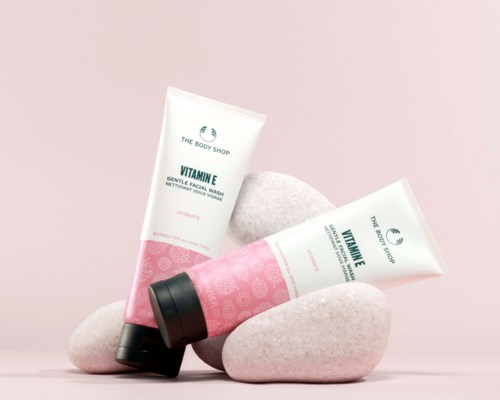 To tubes af The Body Shop Vitamin E gentle facial wash med sorte låg, placeret på rosa sten mod en lyserød baggrund.