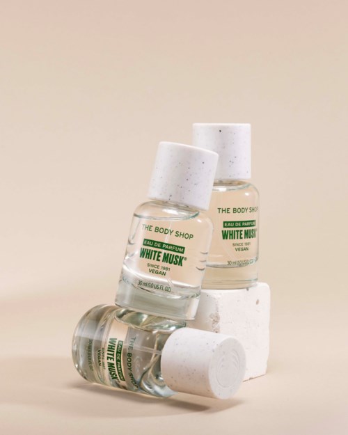 Kolme pientä tuoksupulloa nimeltä White Musk The Body Shopilta, vihreä ja valkoinen pakkauksessa, pinottu ja nojaa valkoisiin palikoihin.