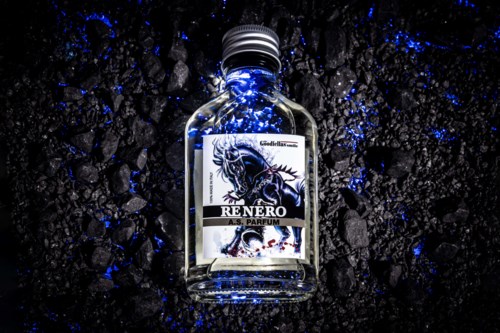 Kleine Glasflasche mit Drachen-Design auf einem Etikett, leuchtet blau auf schwarzer Oberfläche.