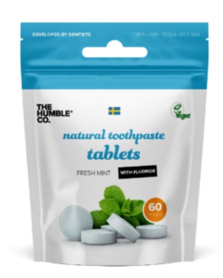 vita tabletter med gröna mintblad på förpackningen för naturliga tandkrämstabletter, med fluortillsats, utvecklade av tandläkare.