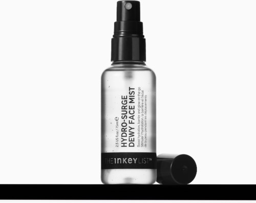 En tydelig sprayflaske merket Hydro-Source Dewy Face Mist med svart lokk ligger ved siden av.