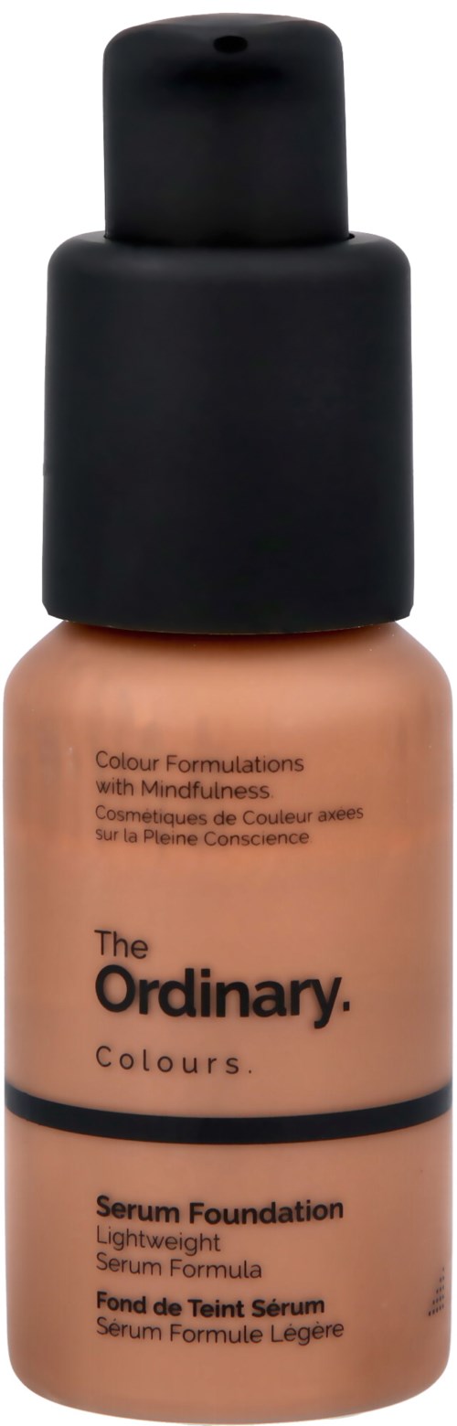 En flaska foundation med svart lock, beige färg, och svart text som beskriver den som serum foundation.