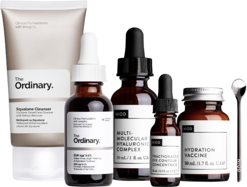 En samling hudpleieprodukter, inkludert rens, serum og en hydrering vaksine, med pipetter og en skje.