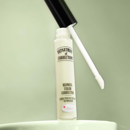 Ein weißer flüssiger Lippenstift mit schwarzem Deckel, beschriftet "Department of Corrections" und "Redness Color Corrector."