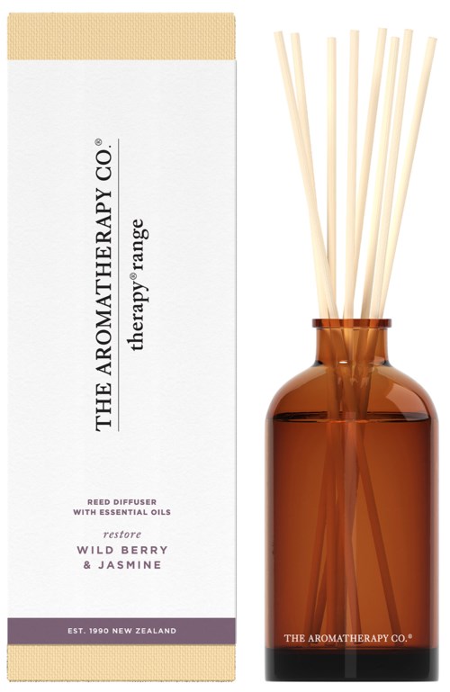 A brown glass bottle with reed diffusers and a white box with purple text about aromatherapy oils.