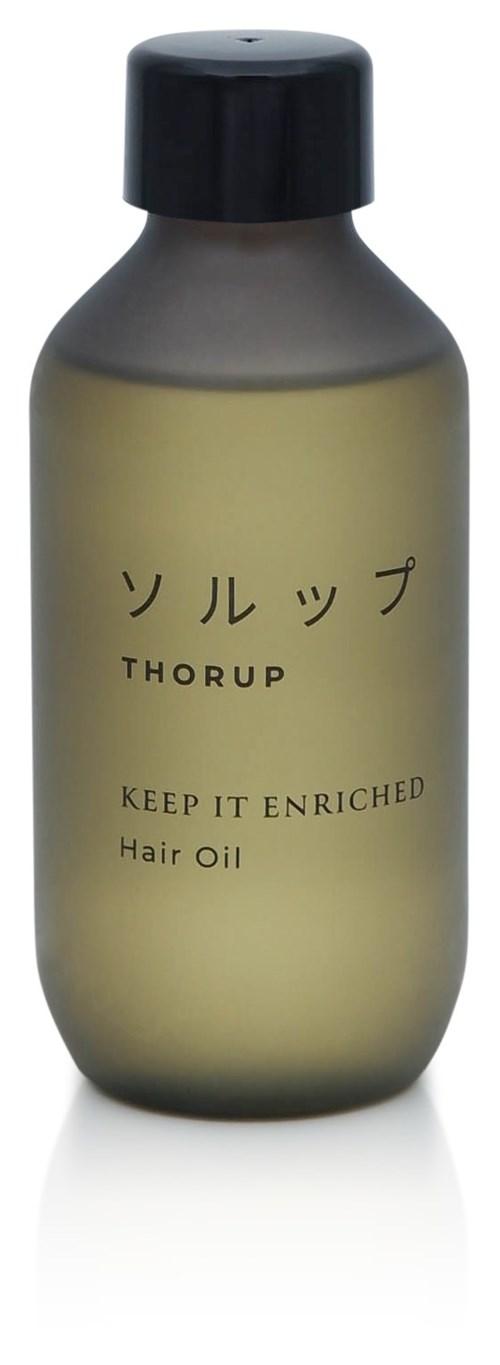 En liten flaska hårolja med svart lock, märkt på japanska och engelska, säger "Keep it enriched."