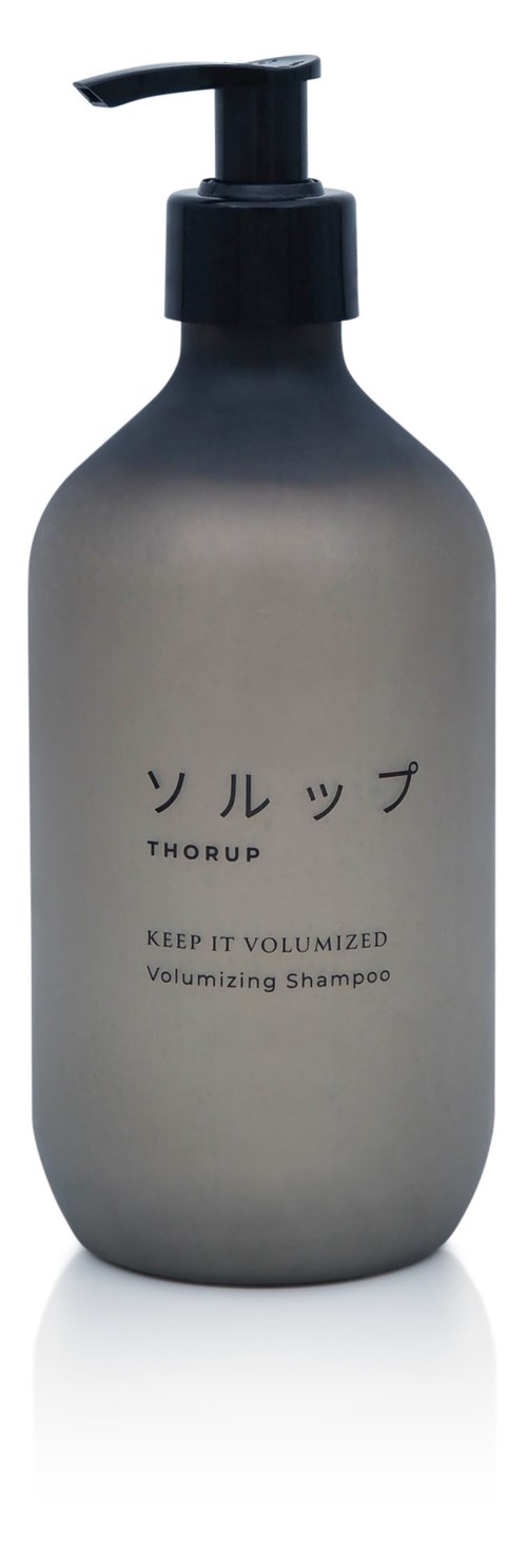 Eine graue Flasche mit schwarzem Pumpkopf, japanischer Text und englisches Label für volumisierendes Shampoo.
