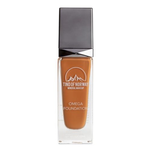 En flaska mineralfoundationmakeup med ett bergslogo, märkt 'Tind of Norway Omega Foundation', i en genomskinlig behållare.
