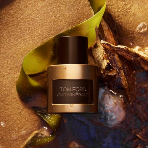 Tom Ford Oud Minerale hajuvesi pullo, joka on jalkapohjan ja merenrannan ympäröimä.