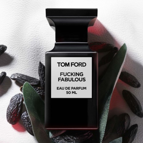 En svart parfymeflaske merket 'Tom Ford Fucking Fabulous' omgitt av mørke steiner og grønne blader.