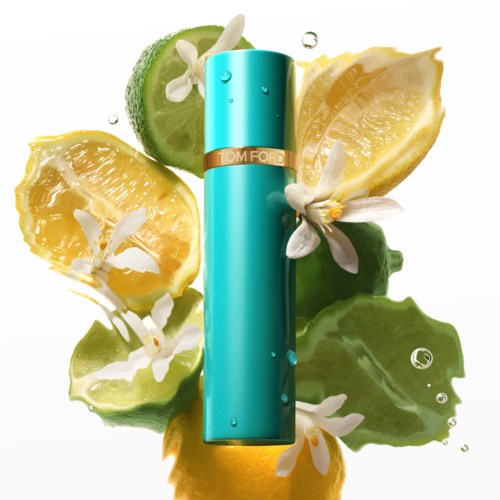 En turkos parfymflaska omgiven av citron, lime och vita blommor med vattendroppar.