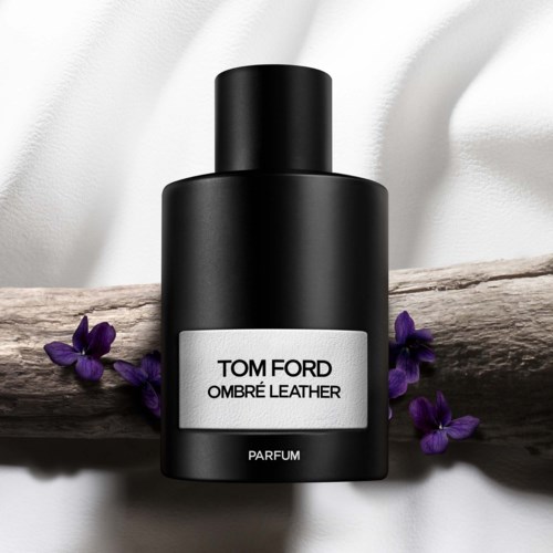 Svart parfymeflaske merket 'Tom Ford Ombré Leather' med lilla blomster rundt på en trestamme.