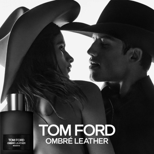 Black and white image of a man and woman facing each other wearing hats, with Tom Ford Ombré Leather perfume bottle visible.