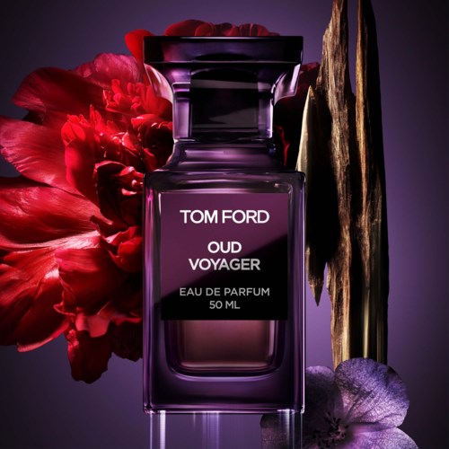 En Tom Ford Oud Voyager parfymeflaske med lilla gradientfarger, omgitt av en rød blomst og et gullfarget dekorativt element.