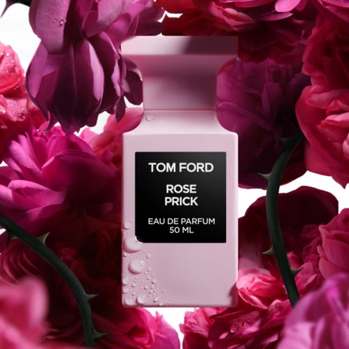 A perfume bottle labeled 'Tom Ford Rose Prick' surrounded by pink flowers.