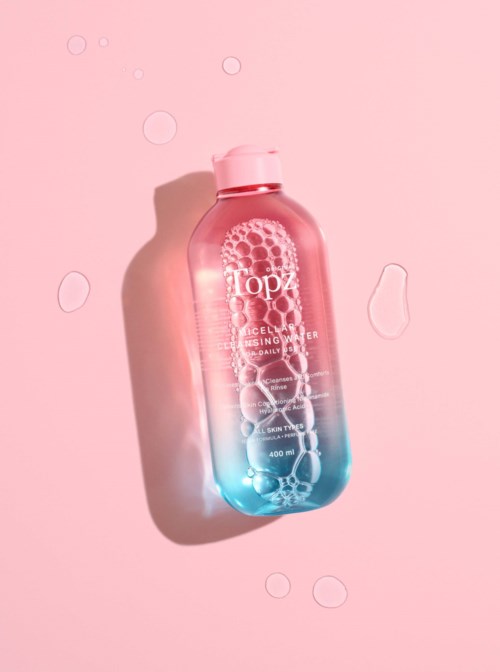 En pink og blå gradientflaske med bobler, mærket 'Topz Cellulose Cleansing Gel' på en pink baggrund.