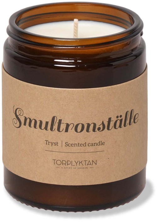 Ett doftljus i en brun glasburk med en beige etikett som säger "Smultronställe."
