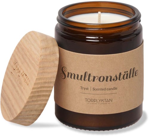 Ett brunt ljusglas med ett trädocka, märkt 'Smultronställe' och 'Tryst Scented candle' i ett glas.