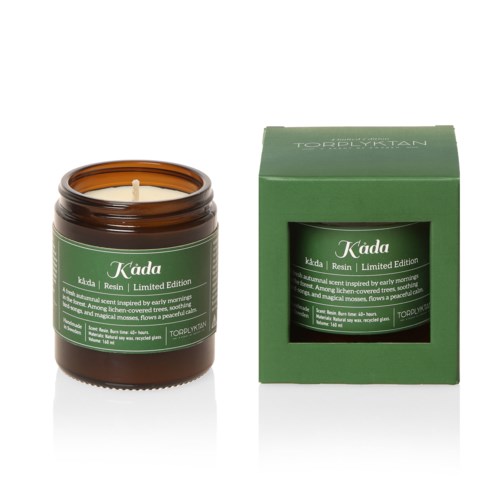 Ett grönt ljus i en burk bredvid dess gröna förpackningslåda, märkt med produktnamn och beskrivning.