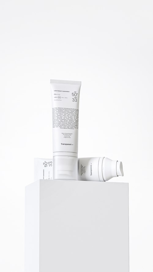 Three white skincare or cosmetic bottles sit on a white block in a clean, minimal setting.