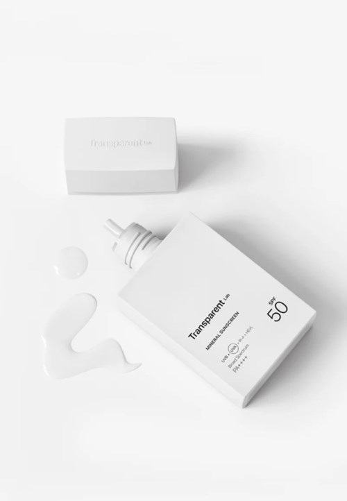 Eine Flasche Sonnencreme mit SPF 50, ein Verschluss und etwas Lotion auf einer weißen Oberfläche.