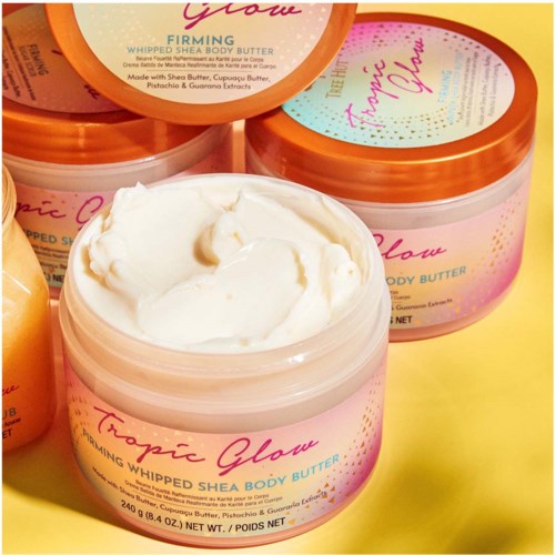 Open pot met romige shea bodyboter met roze, oranje en gele labels, met glad wit botert binnenin.