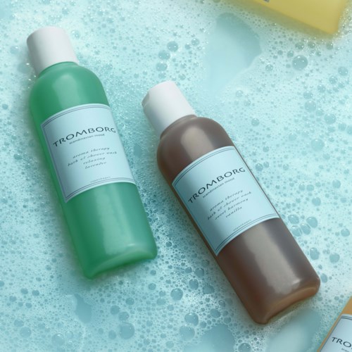 To flasker shampoo eller kropsvask ligger i skummet badevand.