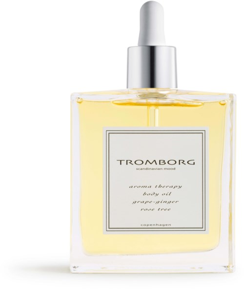 En klar glasflaske med kropsolie, hvid låg og sølvdåse, etiketten siger Tromborg aroma therapy.