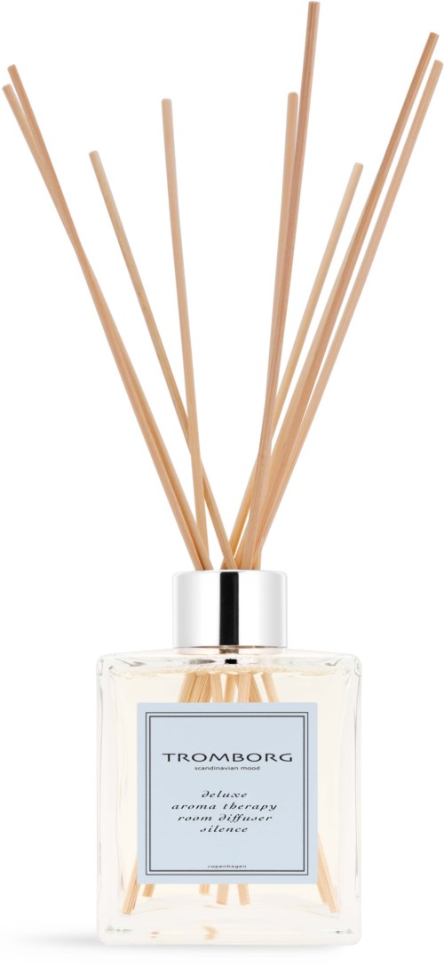 A clear glass bottle with a white label and sticks for scent, used as a diffuser.
