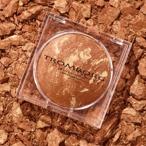 Ett runt, skimrigt bronzeromslag på en texturerad, brunt bakgrund.